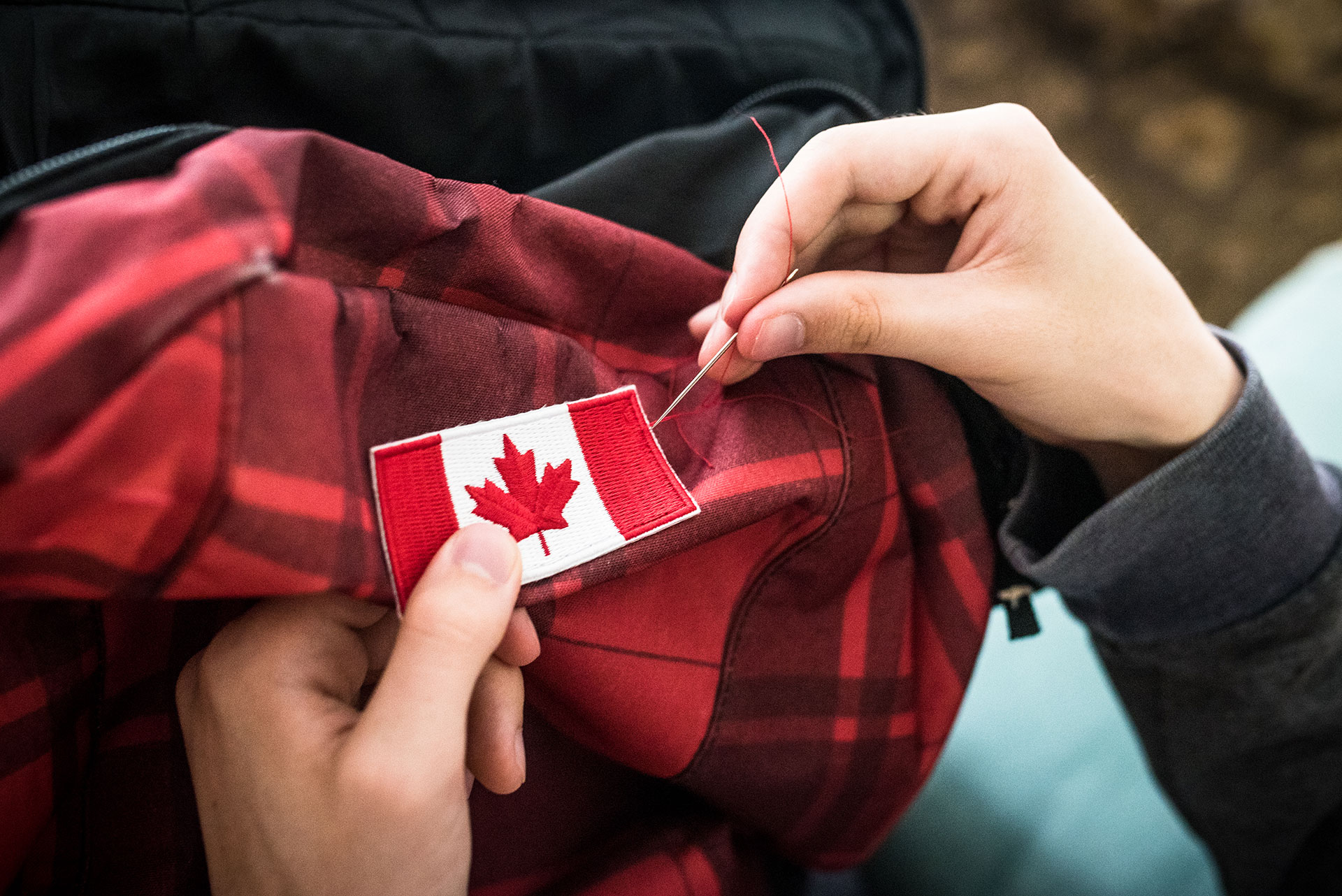 canadian flag patch being sewn onto a backpack